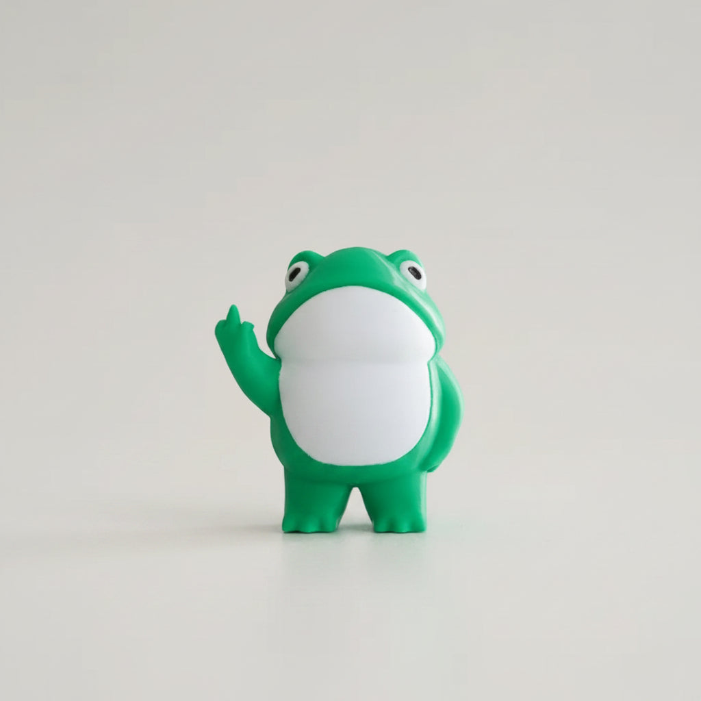 Green frog figurine on a yellow surface with a white background