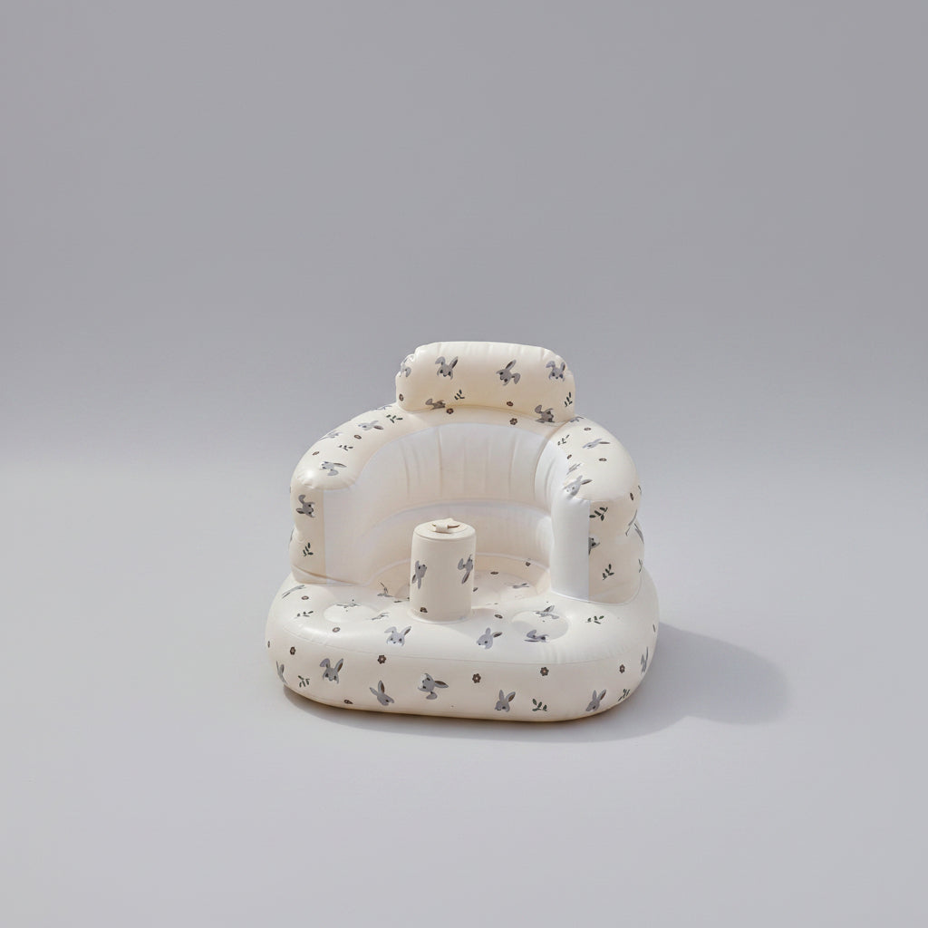 Inflatable baby seat with teddy bear and flowers on a grassy background